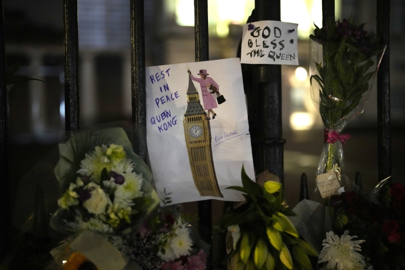 民众绘画放在伦敦白金汉宫外的鲜花旁，悼念英女皇伊利沙伯二世去世。 AP