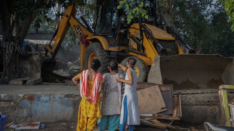 居民无奈看着推土机拆屋。 路透社 居民无奈看着推土机拆屋。 路透社