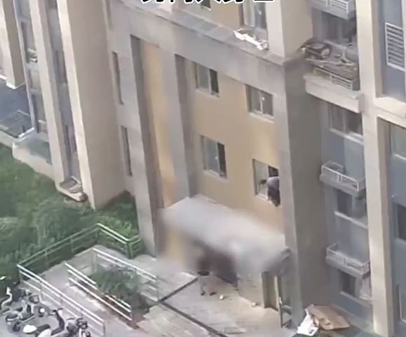 救援人员发现一名孩子倒卧在房檐上。 救援人员发现一名孩子倒卧在房檐上。