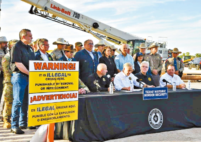 德州州长阿博特(中)18日签署法例,容许德州执法人员拘捕在缺乏法律许可下从墨西哥入境德州的难民,法例将在明年3月生效。 美联社 德州州长阿博特(中)18日签署法例,容许德州执法人员拘捕在缺乏法律许可下从墨西哥入境德州的难民,法例将在明年3月生效。 美联社