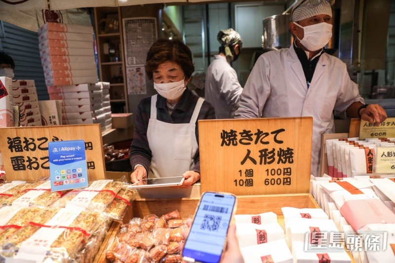 有游客用电子钱包购买当地传统小吃、号称浅草“三大名物”之一的人形烧。