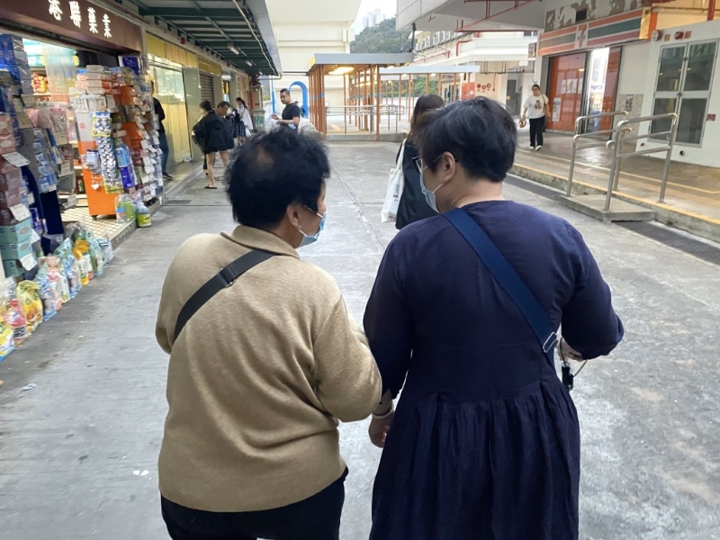 在邨内居住40年的旧街坊李女士（左），带着新入伙、撑拐杖行动不便的陈女士视察邨内环境。 （源琛薇摄）
