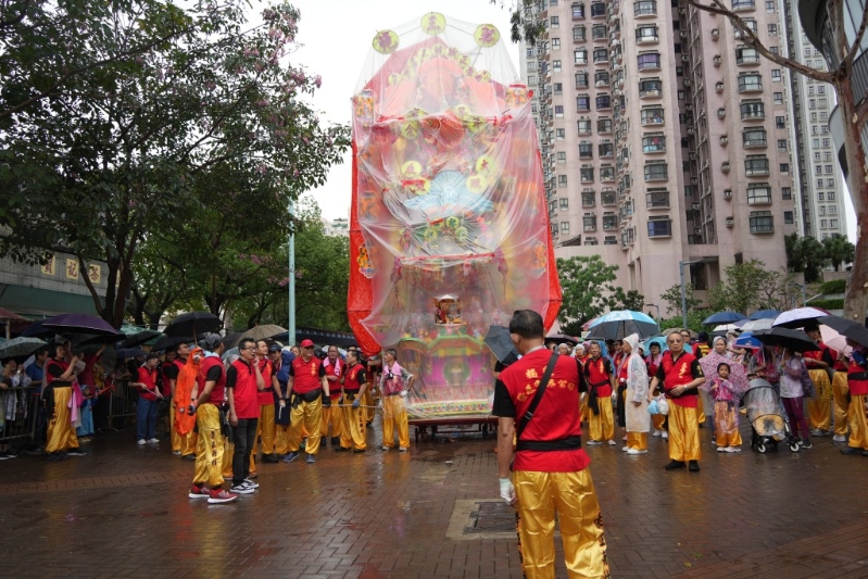 巡游队伍不少人身穿雨衣，纸制花炮亦被被塑料膜包裹。
