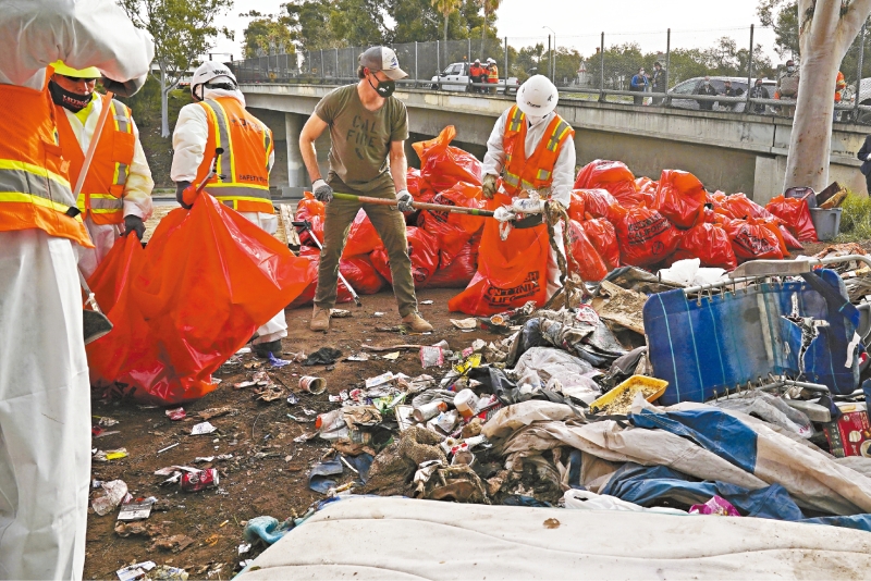 纽森帮忙清理公路旁的无家者营地。