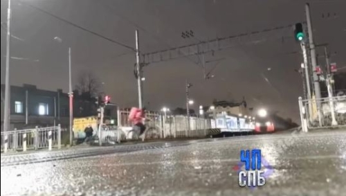 穿粉红外套的外卖员骑单车从左边进入平交道,同时火车在镜头中出现。 穿粉红外套的外卖员骑单车从左边进入平交道,同时火车在镜头中出现。