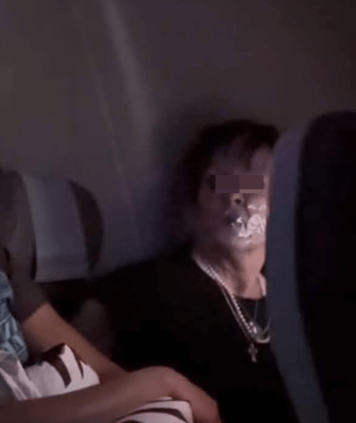 另一张出现在当地媒体的照片,妇人被绑在座位上,嘴巴封上透明胶纸,双目怒瞪着坐在邻座看守她的空姐。.png 另一张出现在当地媒体的照片,妇人被绑在座位上,嘴巴封上透明胶纸,双目怒瞪着坐在邻座看守她的空姐。.png