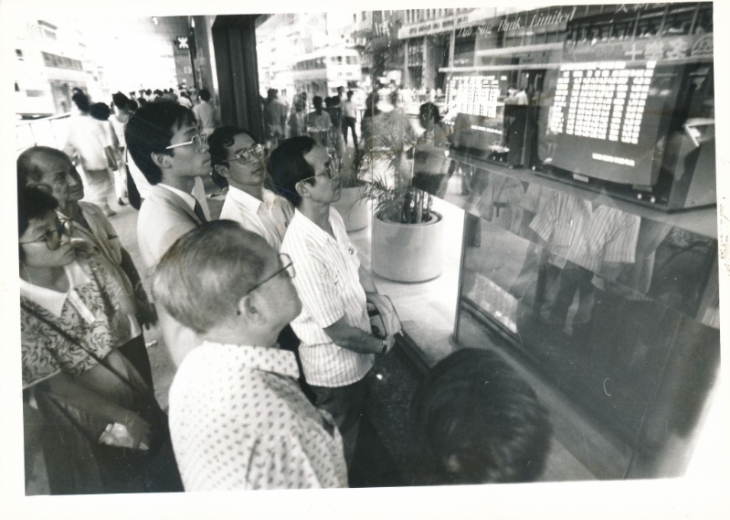 1987年股市疯狂暴泻下,商业区的股价传真吸引大批股民围观市况。资料图片 1987年股市疯狂暴泻下,商业区的股价传真吸引大批股民围观市况。资料图片
