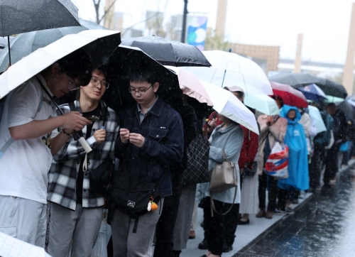 大阪世博开幕首天下大雨,民众狼狈撑伞排队入场。新华社 大阪世博开幕首天下大雨,民众狼狈撑伞排队入场。新华社