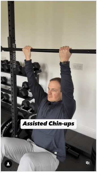 1. 辅助型引体上升步骤:将铃放在训练架上大约胸部高度的位置; 坐在槓铃下方的地面,伸手将发铃举过头顶,反手握住,双手分开与肩同宽。 (IG@olliethompsonhealth) 1. 辅助型引体上升步骤:将铃放在训练架上大约胸部高度的位置; 坐在槓铃下方的地面,伸手将发铃举过头顶,反手握住,双手分开与肩同宽。 (IG@olliethompsonhealth)