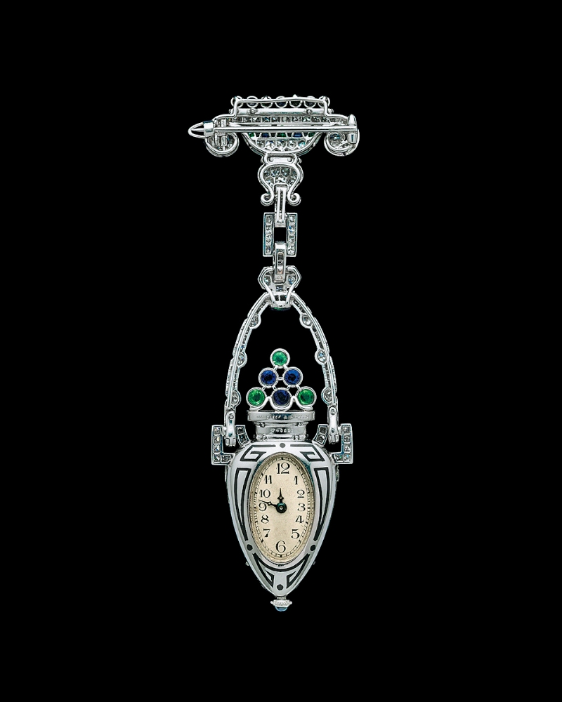 此双耳瓶领表乃Van Cleef & Arpels梵克雅宝约于1925至1930年的作品,铂金镶嵌钻石、祖母绿、蓝宝石、缟玛瑙。 此双耳瓶领表乃Van Cleef & Arpels梵克雅宝约于1925至1930年的作品,铂金镶嵌钻石、祖母绿、蓝宝石、缟玛瑙。