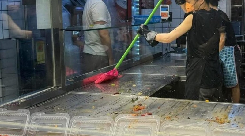 从照片中可见,有店员手持一把红色“扫把”,并举起“扫把”放到平日放置餸兜的食物柜上 从照片中可见,有店员手持一把红色“扫把”,并举起“扫把”放到平日放置餸兜的食物柜上