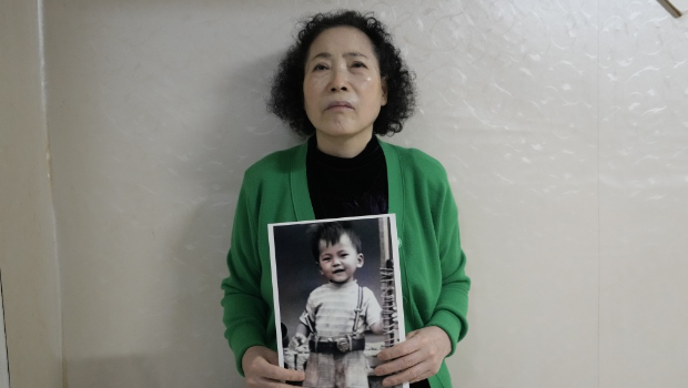 崔英子拿着失踪儿子的照片。 崔英子拿着失踪儿子的照片。