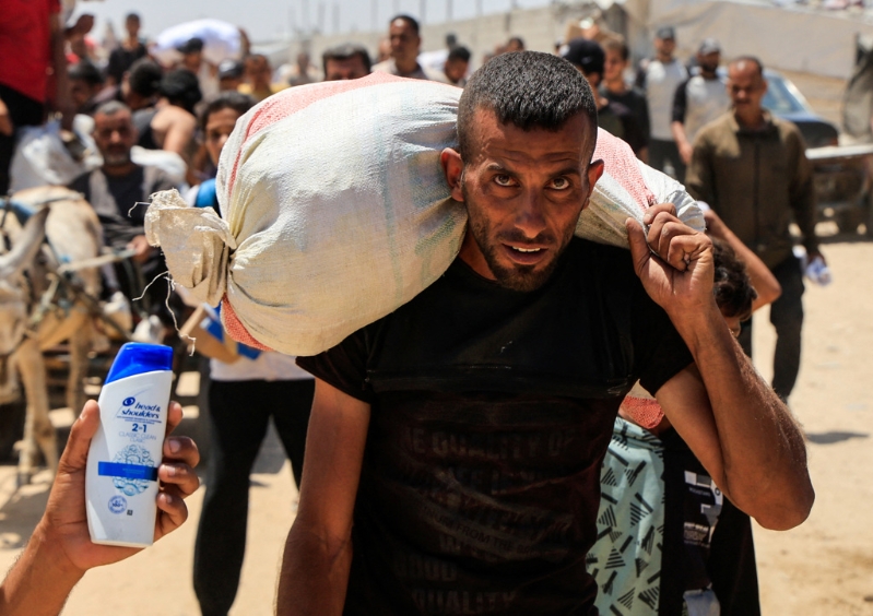 2025年5月28日,加沙巴勒斯坦民众搬运着自GHF人道资源救助点取得的物资。路透社 2025年5月28日,加沙巴勒斯坦民众搬运着自GHF人道资源救助点取得的物资。路透社