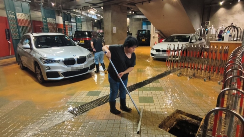 酒店职员慌忙用扫帚扫水。 酒店职员慌忙用扫帚扫水。