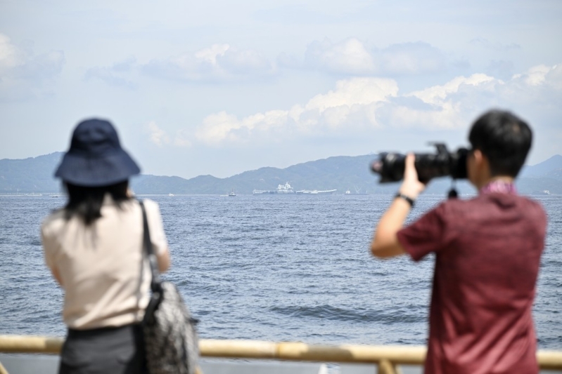 不少市民游客在坚尼地城海傍远眺山东舰。 不少市民游客在坚尼地城海傍远眺山东舰。