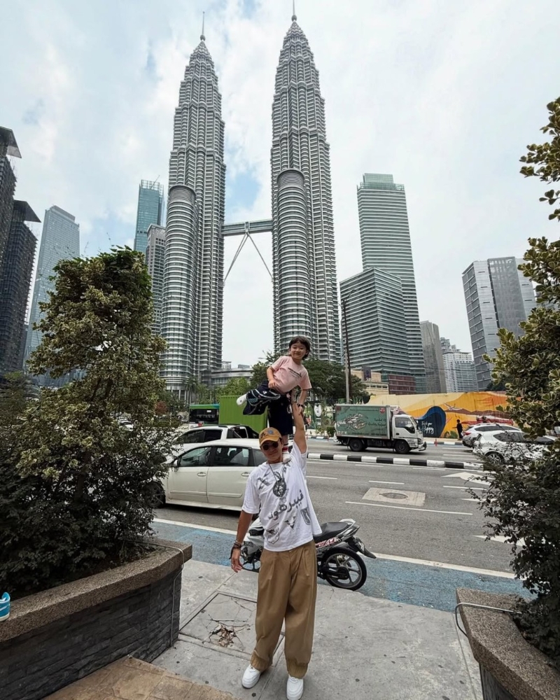 陈山聪举起囝囝影相,以地标双子塔做背景。 陈山聪举起囝囝影相,以地标双子塔做背景。
