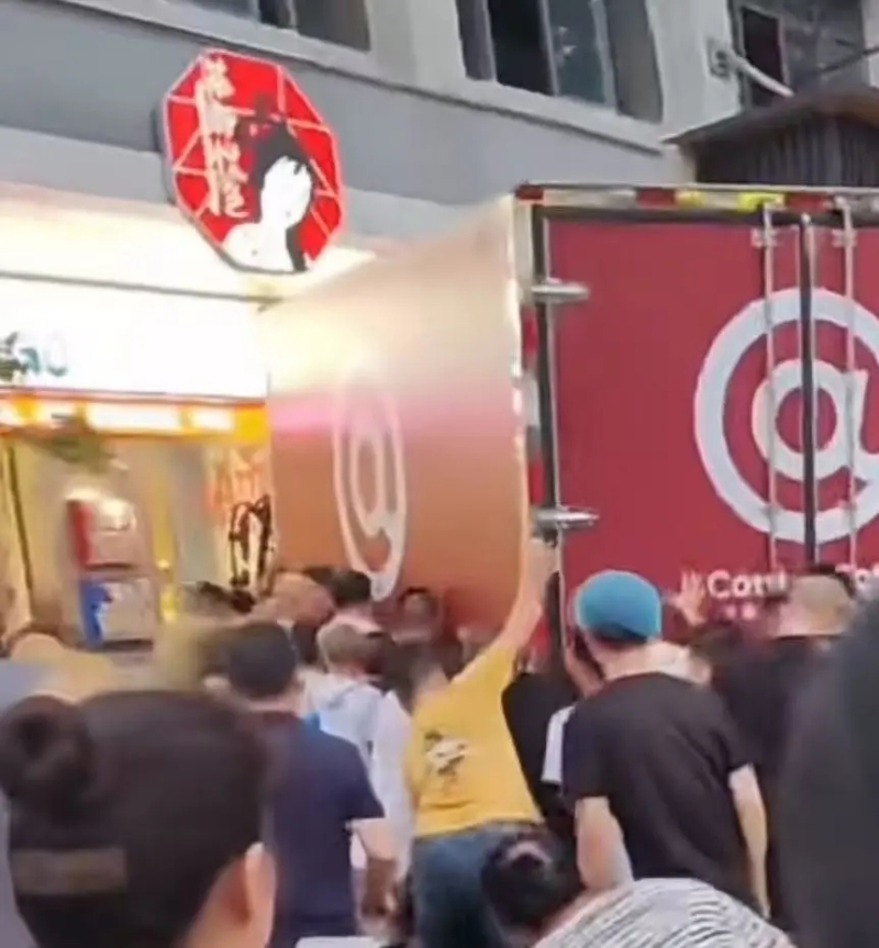 网友发布的现场视频截图可见,众人在挪车救人。 网友发布的现场视频截图可见,众人在挪车救人。