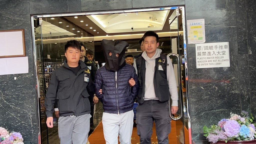 被捕人黑布蒙头,由警员带走。 被捕人黑布蒙头,由警员带走。